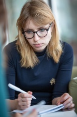 Mädchen mit Brille macht sich Notizen in einem Workshop in Budapest

